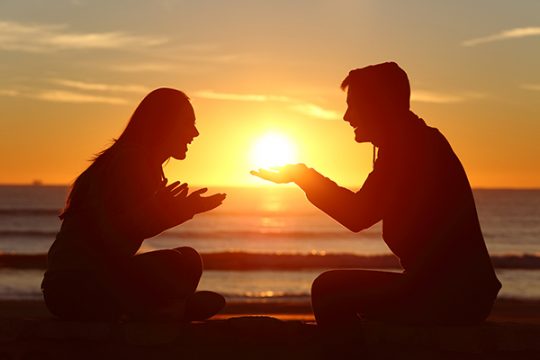 Portrait of a side view of couple or friends silhouette dating and falling in love with a boyfriend giving the sun to his girlfriend outdoors at sunset